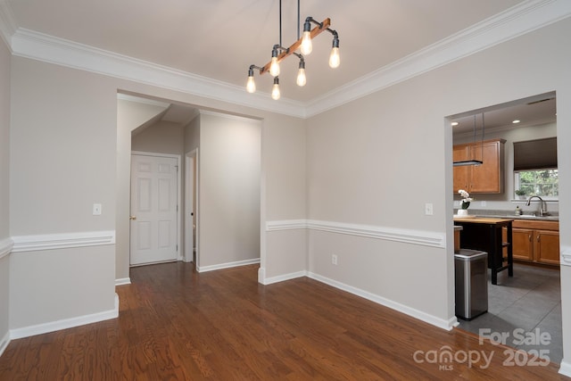 unfurnished dining area featuring ornamental molding, dark wood-style floors, baseboards, and a sink