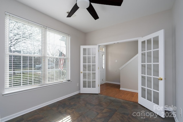 unfurnished room with a ceiling fan, french doors, baseboards, and a healthy amount of sunlight