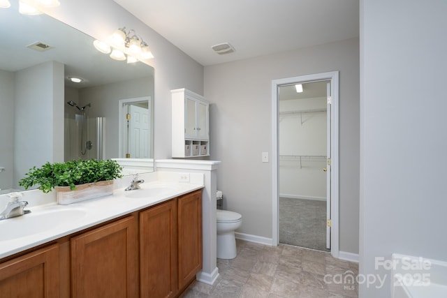 bathroom with double vanity, a shower, visible vents, and a sink