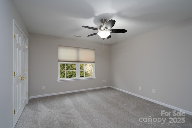 empty room featuring a ceiling fan, carpet, visible vents, and baseboards