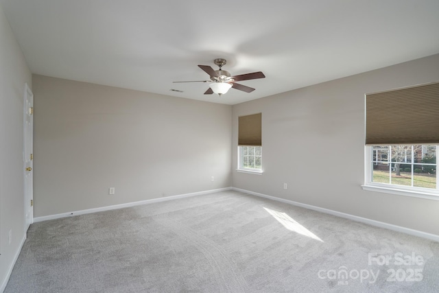 carpeted spare room with visible vents, baseboards, and ceiling fan