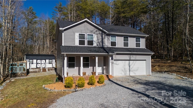 traditional-style house featuring a front yard, gravel driveway, an attached garage, covered porch, and a shingled roof