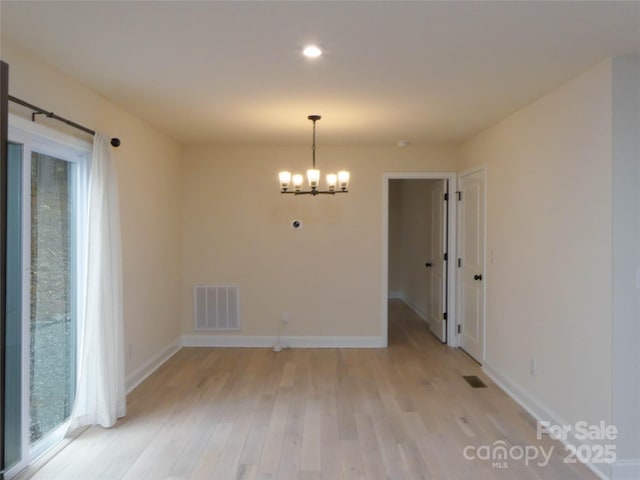 unfurnished dining area featuring a wealth of natural light, light wood-type flooring, visible vents, a notable chandelier, and baseboards