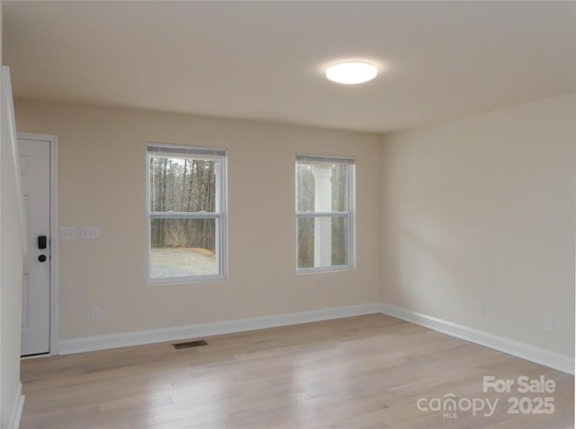 spare room featuring visible vents, baseboards, and light wood-style floors