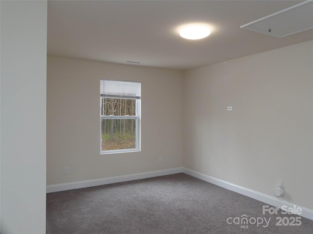 spare room with carpet flooring, attic access, and baseboards