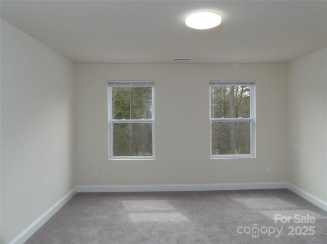 spare room featuring light carpet, visible vents, and baseboards