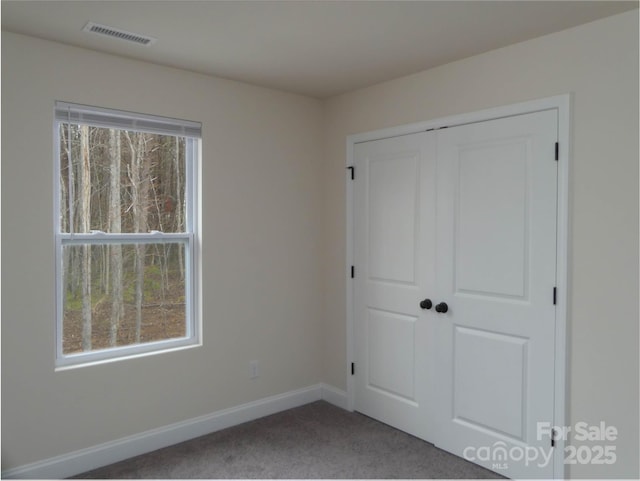 unfurnished bedroom with visible vents, baseboards, carpet floors, and a closet