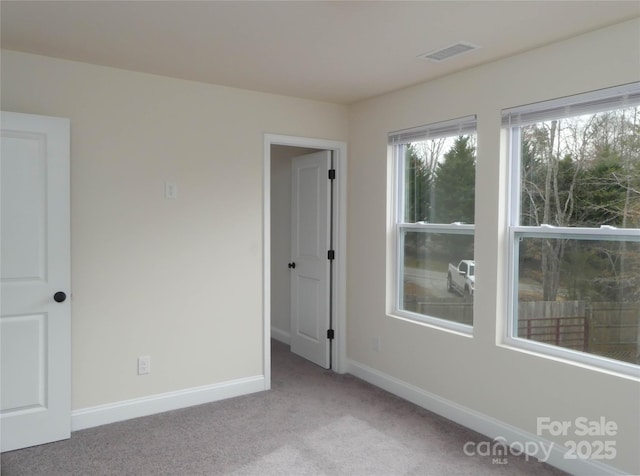 carpeted spare room with baseboards and visible vents