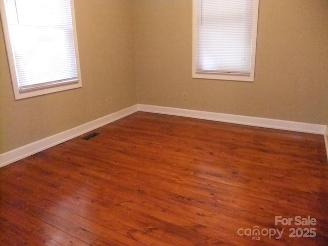 empty room featuring visible vents, baseboards, and wood finished floors