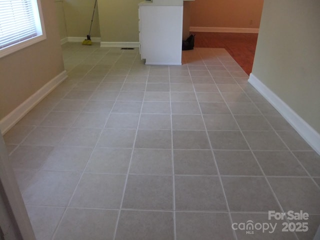 basement featuring light tile patterned flooring and baseboards