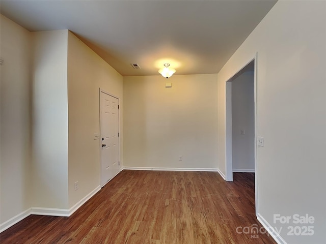 unfurnished room featuring wood finished floors, visible vents, and baseboards