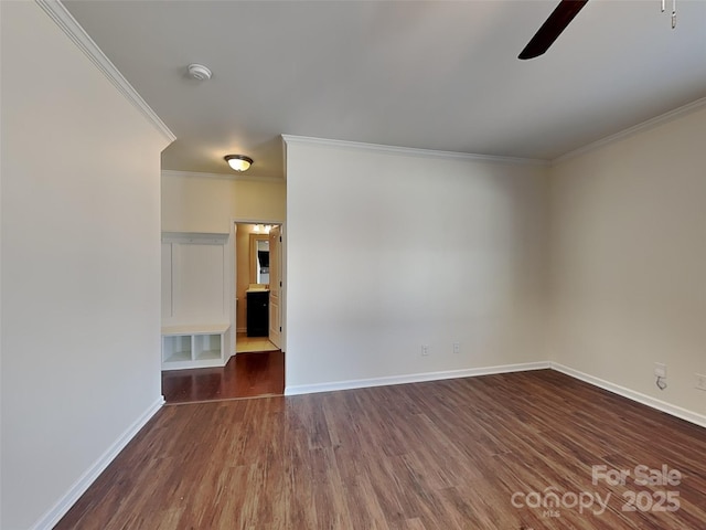 spare room with crown molding, a ceiling fan, dark wood-style flooring, and baseboards