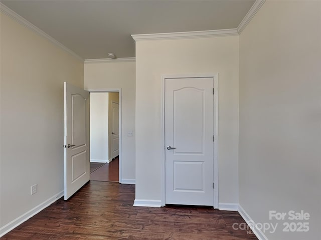 unfurnished bedroom with dark wood finished floors, crown molding, and baseboards