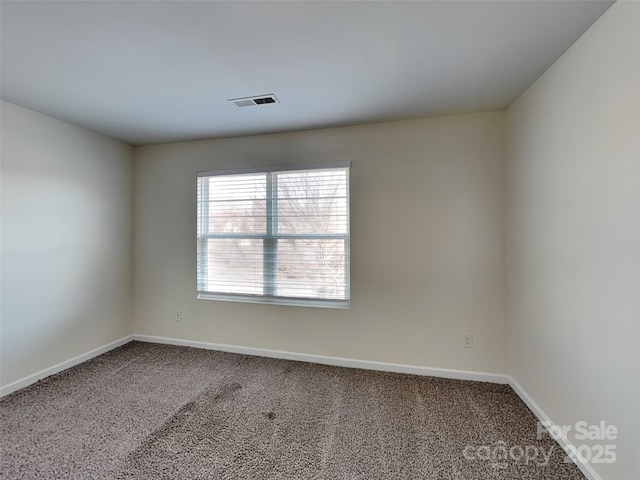 carpeted spare room with visible vents and baseboards