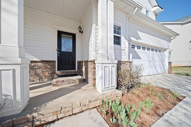 entrance to property featuring stone siding, driveway, and a garage