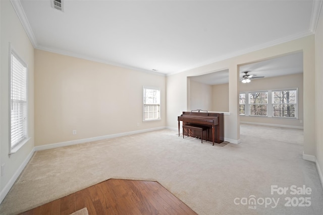 unfurnished room featuring visible vents, crown molding, ceiling fan, baseboards, and carpet floors