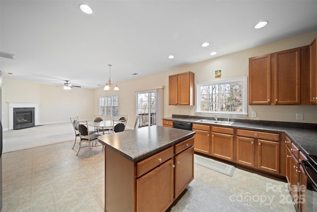 kitchen with dark countertops, black dishwasher, a fireplace, a ceiling fan, and a sink