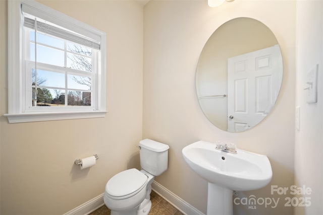 half bathroom with tile patterned floors, toilet, baseboards, and a sink