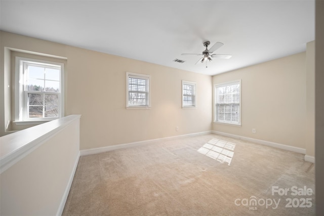 carpeted spare room with visible vents, a ceiling fan, and baseboards