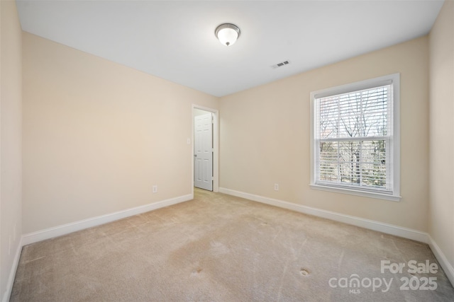 carpeted spare room featuring baseboards and visible vents