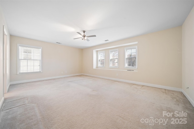 carpeted empty room featuring visible vents, baseboards, a healthy amount of sunlight, and ceiling fan