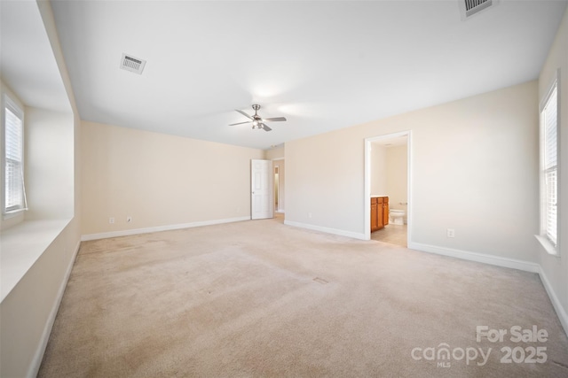 unfurnished room featuring light carpet, visible vents, and a wealth of natural light