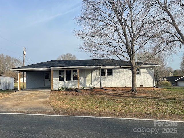 ranch-style home featuring an attached carport, covered porch, brick siding, and driveway