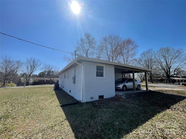 view of side of home with brick siding, an attached carport, a lawn, central AC unit, and crawl space