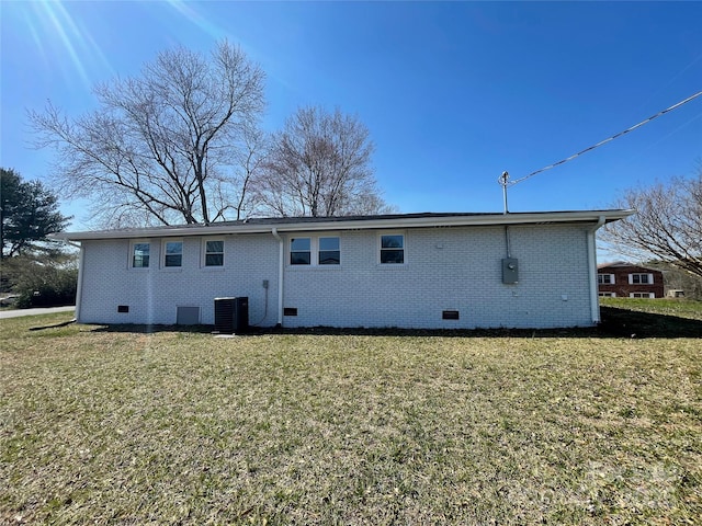 rear view of house featuring a yard, central AC unit, brick siding, and crawl space