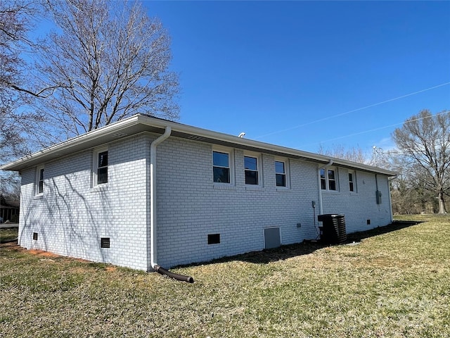 back of house with crawl space, a yard, central AC unit, and brick siding