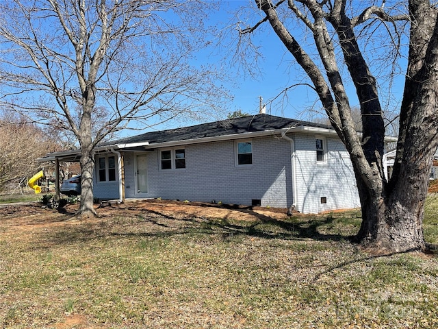 back of house featuring an attached carport, a yard, brick siding, and crawl space