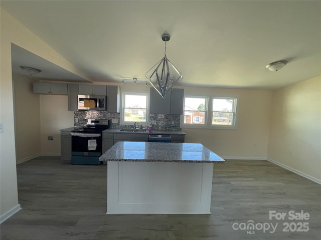 kitchen with backsplash, appliances with stainless steel finishes, light wood-style flooring, and light stone countertops