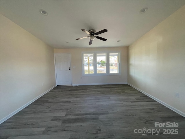 spare room featuring baseboards, dark wood-type flooring, and ceiling fan