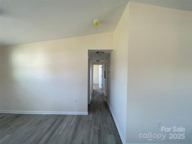 interior space with baseboards, dark wood-type flooring, and vaulted ceiling