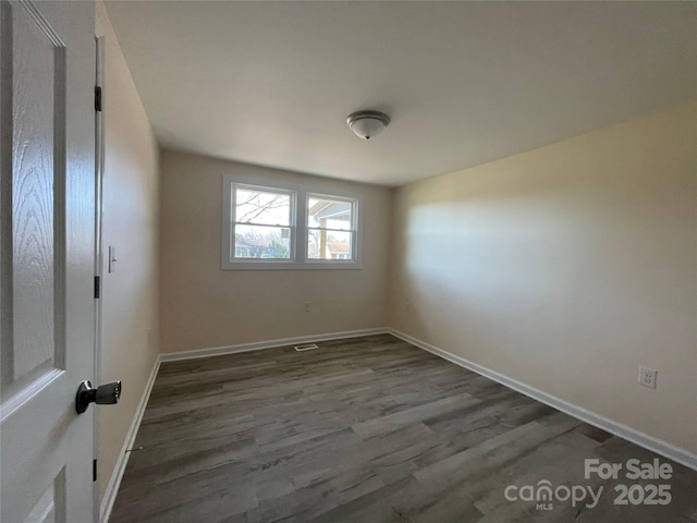 spare room with dark wood-style floors and baseboards