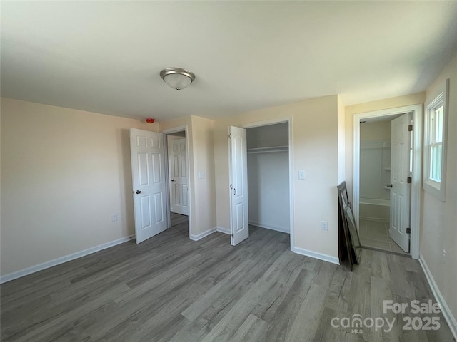 unfurnished bedroom featuring a closet, baseboards, and wood finished floors