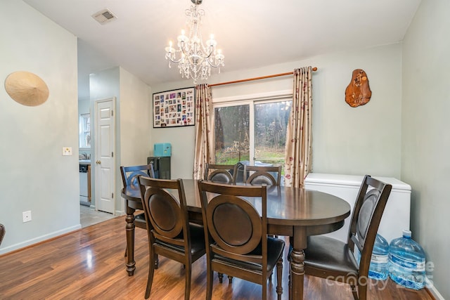 dining space featuring an inviting chandelier, wood finished floors, visible vents, and baseboards