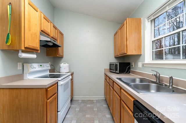 kitchen featuring stainless steel microwave, stone finish flooring, under cabinet range hood, electric range, and a sink