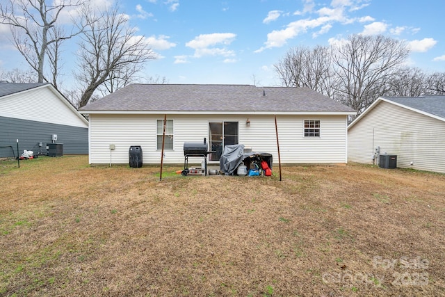 rear view of house featuring a lawn and central AC