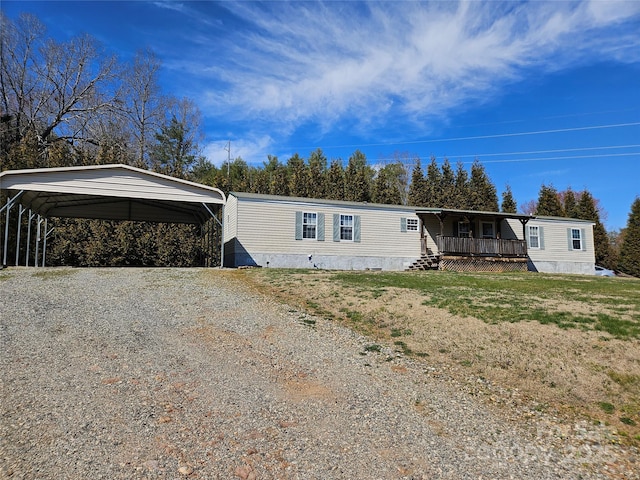 manufactured / mobile home with a carport, gravel driveway, and a front yard