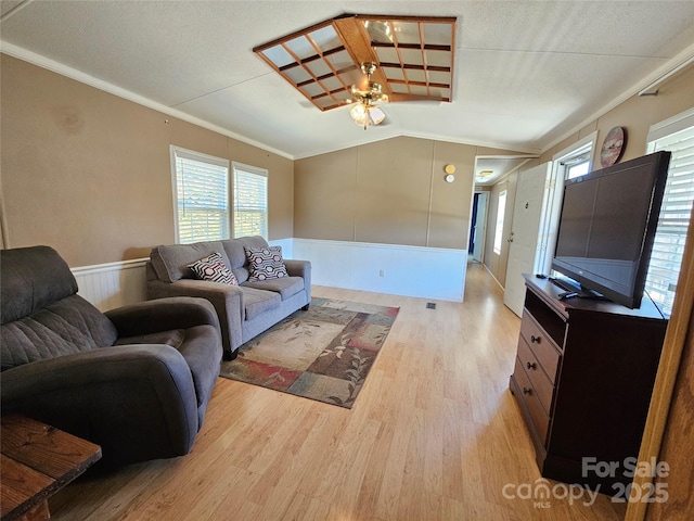 living area featuring ornamental molding, light wood-style floors, wainscoting, ceiling fan, and vaulted ceiling