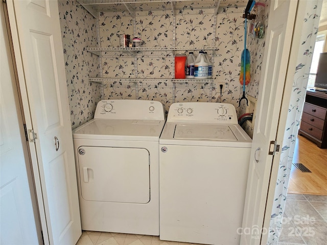 laundry room with laundry area, independent washer and dryer, and wallpapered walls