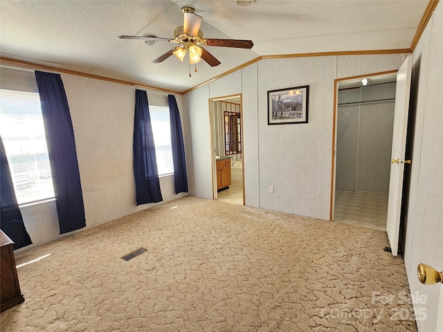 unfurnished bedroom with crown molding, lofted ceiling, and carpet floors