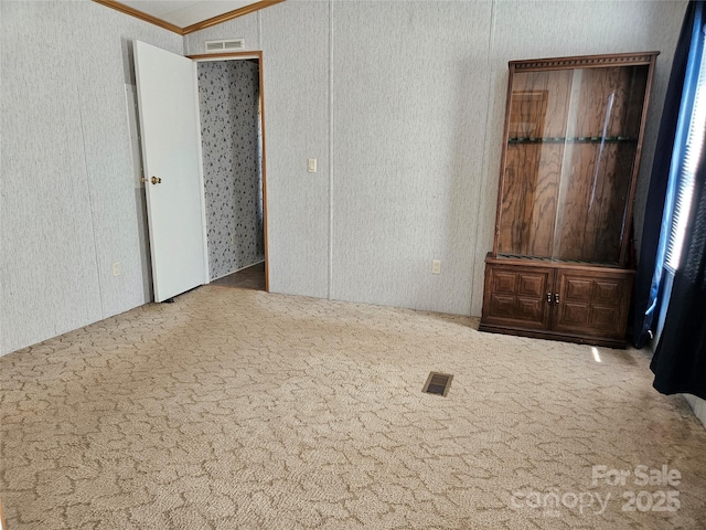 unfurnished bedroom with crown molding, visible vents, and carpet floors