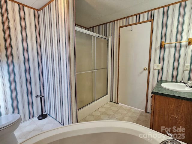 full bathroom featuring wallpapered walls, toilet, vanity, and a stall shower