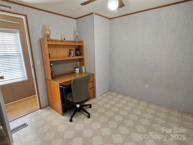 home office featuring visible vents, wallpapered walls, ceiling fan, and ornamental molding