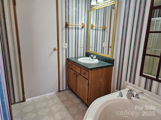 bathroom featuring tile patterned floors, wallpapered walls, and a sink