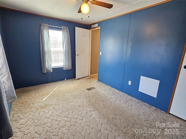 carpeted empty room with visible vents and a ceiling fan