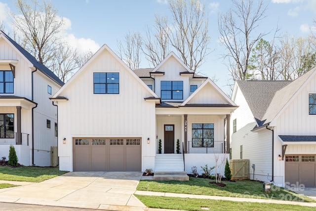 2021 S St, Charlotte, NC 28208 - view of front of home with an attached garage, board and batten siding, driveway, a front yard, and covered porch