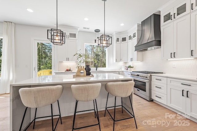 2013 S St, Charlotte, NC 28208 - kitchen with stainless steel range, custom range hood, a kitchen island, light countertops, and recessed lighting